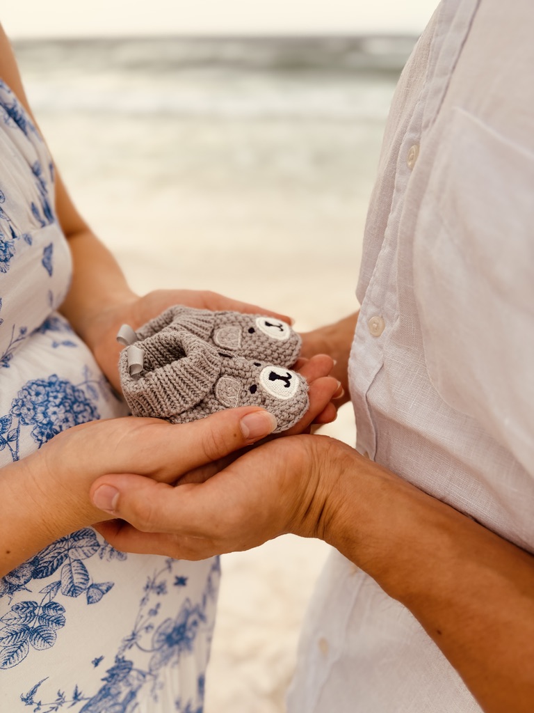 Expectant parents holding tiny knitted baby shoes together